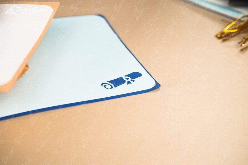 May include: A blue and white desk mat with a blue diploma icon in the center. The mat has a dark blue border.