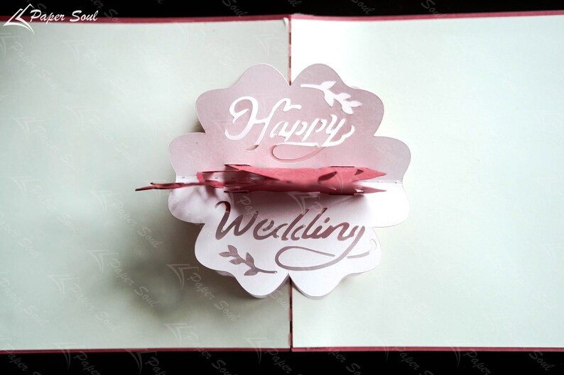 Pode incluir: Um cart&atilde;o pop-up rosa e branco com as palavras "Happy Wedding" em uma fonte decorativa.
