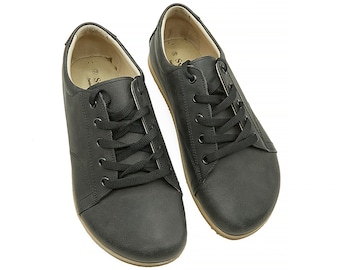 May include: A pair of black leather lace-up shoes with a brown rubber sole.