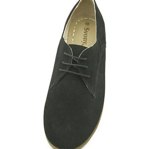 May include: Black suede lace-up shoes with a brown sole. The shoes have a label that says "Svovy" on the inside.