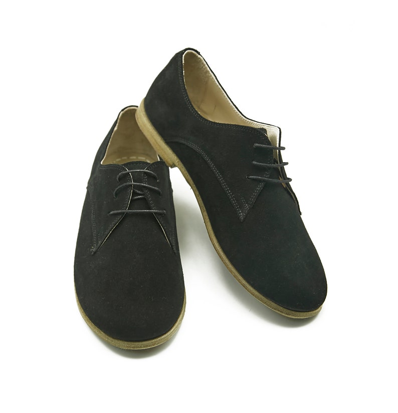 May include: A pair of black suede lace-up shoes with a brown sole.