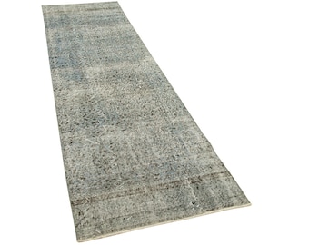 May include: A long, rectangular rug with a faded, distressed look. The rug has a blue and gray color scheme with a subtle pattern throughout. The rug is made of wool and has a soft, comfortable texture.