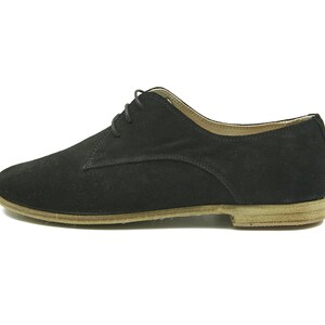 May include: Black suede lace-up shoes with a brown leather sole.