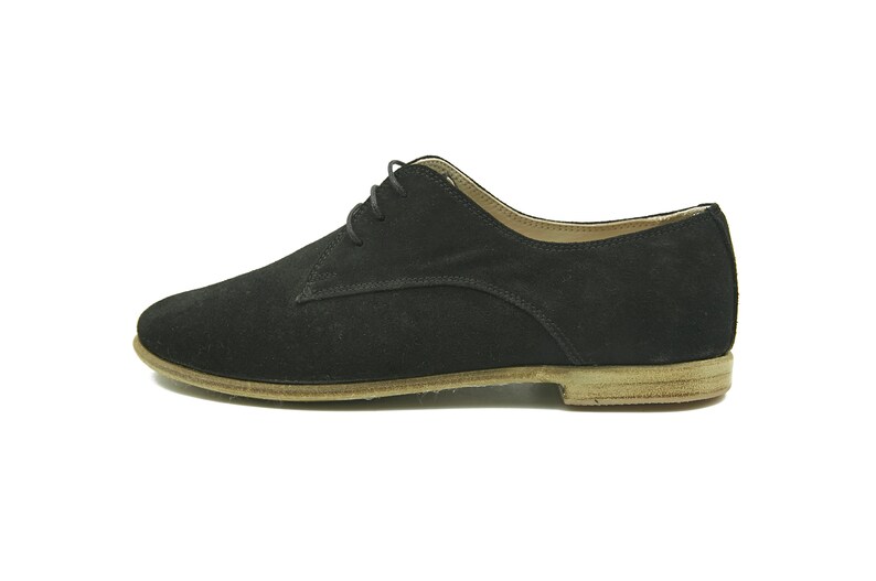 May include: Black suede lace-up shoes with a brown leather sole.