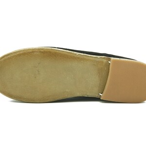 May include: The bottom of a black suede shoe with a brown leather sole.