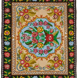 May include: A rectangular, hand-woven rug with a floral design. The rug features a central light blue medallion with a bouquet of red, pink, and yellow flowers. The border is black with repeating floral patterns in red, yellow, and blue. The rug's dimensions are approximately 60 inches by 40 inches.