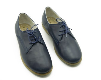 May include: A pair of navy blue leather lace-up shoes with a brown sole.