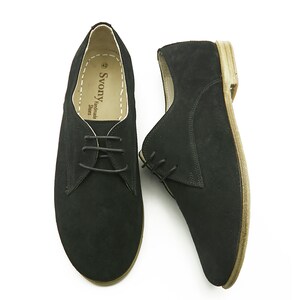 May include: A pair of black suede lace-up shoes with a brown sole. The shoes are handmade by Svonya Shoes.