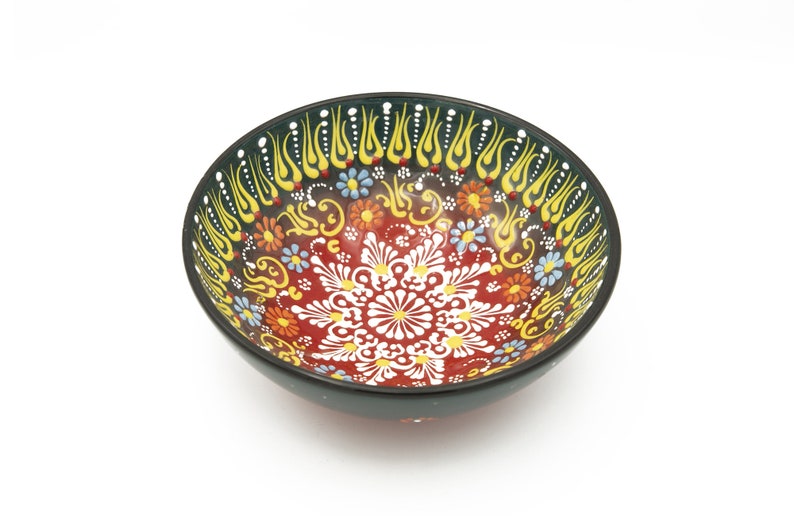 K&ouml;nnte beinhalten: Eine rote und schwarze Keramiksch&uuml;ssel mit einem bunten floralen und geometrischen Design. Die Sch&uuml;ssel hat einen schwarzen Rand und eine wei&szlig;e Mitte mit einem floralen Muster.