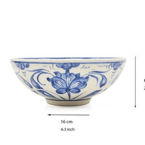 Puede incluir: Un cuenco de cerámica blanca con un diseño floral azul. El cuenco tiene 16 cm de ancho y 6 cm de alto.