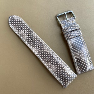 Könnte beinhalten: Ein hellbraunes Lederarmband mit einem strukturierten Muster. Das Armband hat eine silberne Schließe.