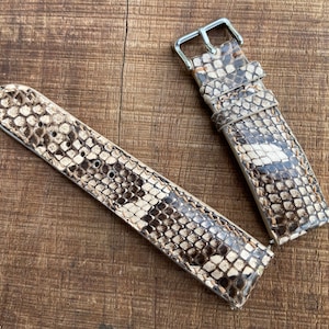 Puede incluir: Dos correas de reloj de piel de serpiente beige y marrón con hebillas plateadas.