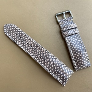 May include: A light brown leather watch strap with a snakeskin pattern and silver buckle.