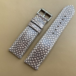 Könnte beinhalten: Ein braunes Lederarmband mit einem weißen Schlangenhautmuster. Das Armband hat eine silberne Schließe.