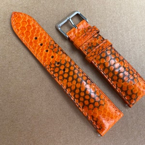 Könnte beinhalten: Orangefarbenes Lederarmband mit einem strukturierten Schlangenhautmuster.