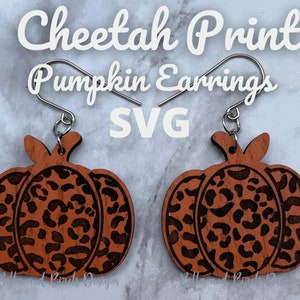 May include: A pair of wooden pumpkin earrings with a cheetah print design. The earrings are brown with black cheetah spots and have silver hooks.