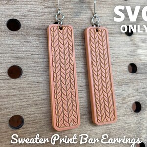 Könnte beinhalten: Zwei pfirsichfarbene Ohrringe in Stabform mit einem Strickmuster. Die rechteckigen Ohrringe haben ein strukturiertes Design und sind an silberfarbenen Haken aufgehängt. Der Text "SVG ONLY" ist sichtbar. Der Text "Sweater Print Bar Earrings" befindet sich unten.