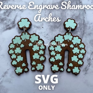 Puede incluir: Un par de pendientes de madera con forma de arcos, decorados con un patrón de trébol en verde claro. Los pendientes están hechos de madera marrón y tienen un gancho plateado.