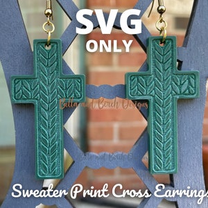 May include: A pair of green cross-shaped earrings with a knitted pattern. The earrings are hanging from gold hooks. The text "SVG ONLY" and "Sweater Print Cross Earrings" is visible in the image.