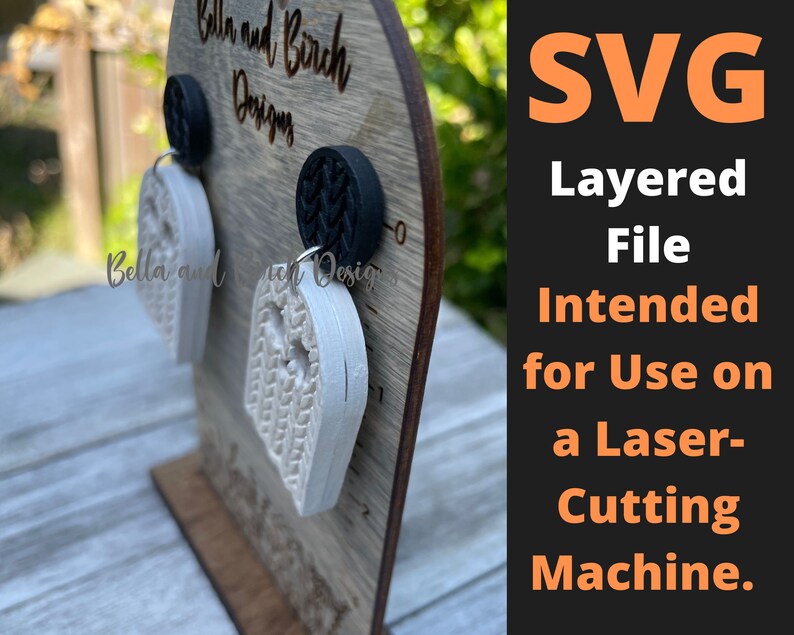 May include: A pair of white layered ghost-shaped earrings on a wooden display stand. The earrings are intended for use with a laser cutting machine. The text "SVG Layered File Intended for Use on a Laser-Cutting Machine." is displayed on a black background.