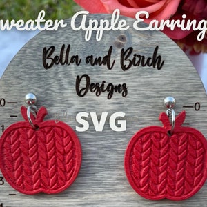 May include: Red apple-shaped earrings with a knitted sweater pattern. The earrings are displayed on a wooden board with the text "Bella and Birch Designs SVG" on it.