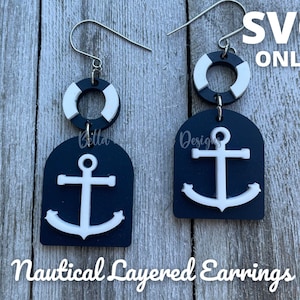 May include: Nautical-themed layered earrings with a navy blue and white color scheme. Each earring features a white anchor design on a navy blue arched base, topped with a white and navy blue life preserver. The text "SVG ONLY" is visible.