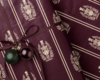 Geschenkpapier mit Nussknackermotiv in Burgunderrot. Dunkelrote Weihnachtsgeschenkrolle. Elegantes weinrotes Festtagspapier. Traditionelles gestreiftes Nussknackermotiv.
