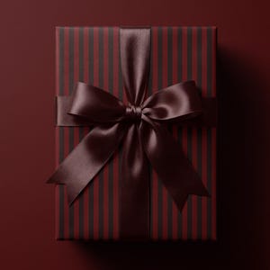 May include: A rectangular gift box wrapped in dark red and black vertical striped paper. The package is tied with a wide, smooth, dark brown satin ribbon that is fashioned into a large, centered bow with two long, pointed tails extending downward.