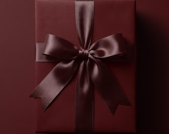 Puede incluir: Una caja de regalo rectangular envuelta en papel de color burdeos profundo sólido. La caja está atada con una cinta de satén de color burdeos oscuro a juego que forma un lazo grande y centrado con dos extremos largos y puntiagudos.