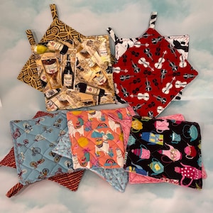 May include: Set of eight quilted pot holders with various patterns. The patterns include wine bottles, musical instruments, bicycles, llamas, and teapots. The pot holders are all square and have a loop handle.