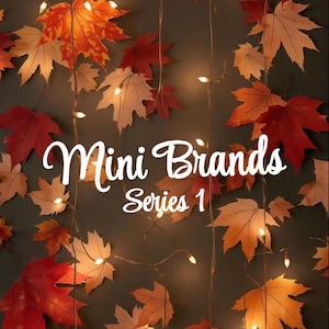 May include: Autumn-themed image with maple leaves in shades of red, orange, and tan, arranged against a dark green backdrop. String lights are interspersed among the leaves. The text "Mini Brands Series 1" is displayed in a cursive font.