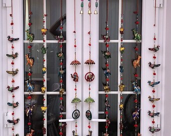 May include: A set of eight colorful hanging decorations with various animal and umbrella designs. Each decoration features a string of beads with small bells at the bottom. The decorations are hung on a white door with glass panels.