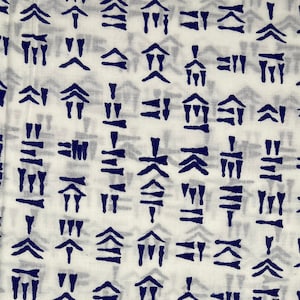 Puede incluir: Tela blanca con un patrón repetitivo de formas abstractas azules. Las formas son una combinación de triángulos, líneas y cuadrados.