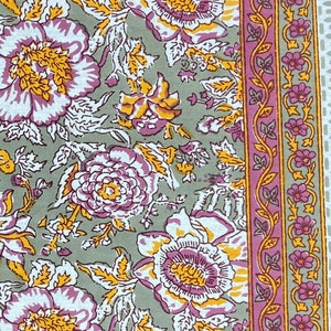 May include: A gray fabric with a pink and yellow floral pattern. The fabric has a pink border with a floral design.