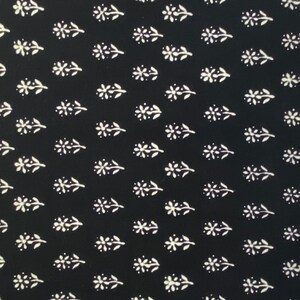 May include: A folded black fabric with a repeating pattern of white floral sprigs. The sprigs are evenly spaced across the fabric, creating a consistent and visually appealing design. The fabric appears to be a medium weight, suitable for various sewing projects.