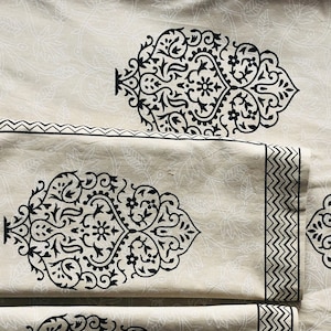 Puede incluir: Juego de tela beige con un diseño floral negro. El juego incluye una pieza rectangular grande, dos piezas rectangulares más pequeñas y dos piezas cuadradas. Los bordes de las piezas rectangulares tienen un borde negro en zigzag.