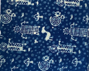 Pode incluir: Um tecido azul com um padrão branco de figuras estilizadas e redemoinhos. O tecido tem um aspecto texturizado, tecido à mão.