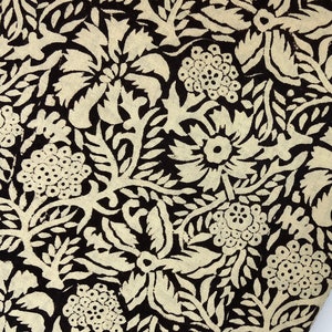 May include: Black fabric with a white floral pattern. The fabric is folded and draped over a wooden hanger.