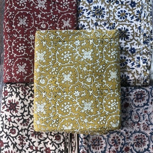 May include: Five different fabric swatches with floral patterns. The fabrics are in shades of red, blue, yellow, and white.