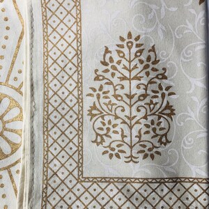 Puede incluir: Tela blanca con un borde dorado y un diseño floral dorado. La tela tiene una textura sutil.