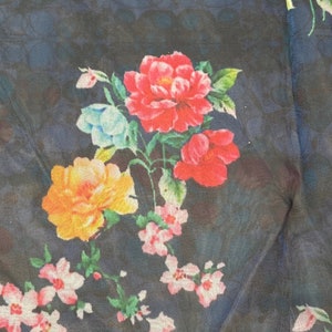 Puede incluir: Una tela azul oscuro con un estampado floral con flores rosas, rojas, amarillas y azules. Las flores est&aacute;n dispuestas en un patr&oacute;n aleatorio y est&aacute;n rodeadas de hojas verdes.