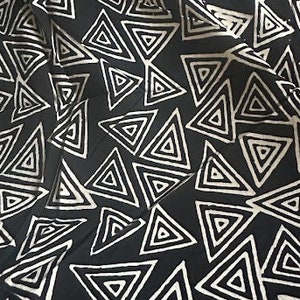 Puede incluir: Tela negra y blanca con un patrón repetitivo de círculos concéntricos que forman triángulos.