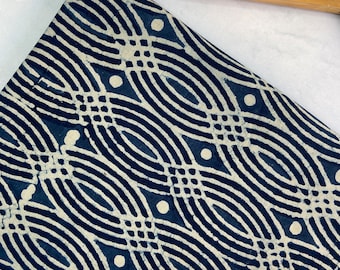 May include: Blue and white fabric with a geometric pattern of wavy lines and circles. The fabric is folded and draped over a wooden hanger.