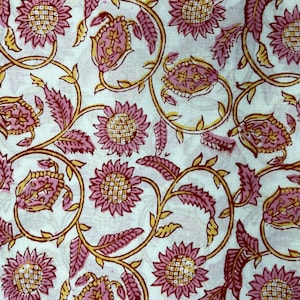 Pode incluir: Tecido branco com um padrão floral rosa e amarelo. O padrão apresenta flores estilizadas com um centro em forma de grade e folhas.