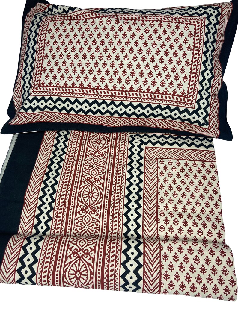 Puede incluir: Un juego de cama de algod&oacute;n con estampado negro y rojo con una funda de almohada. La ropa de cama presenta un dise&ntilde;o geom&eacute;trico con detalles en negro, blanco y rojo.