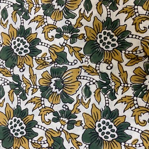 May include: A white fabric with a repeating pattern of green and yellow flowers. The flowers have a white center with small green dots.