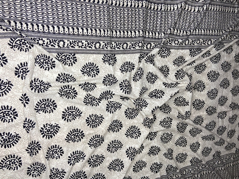 Peut inclure: Tissu blanc avec un motif paisley noir. Le tissu est pli&eacute; et a une bordure avec un motif noir et blanc plus petit.