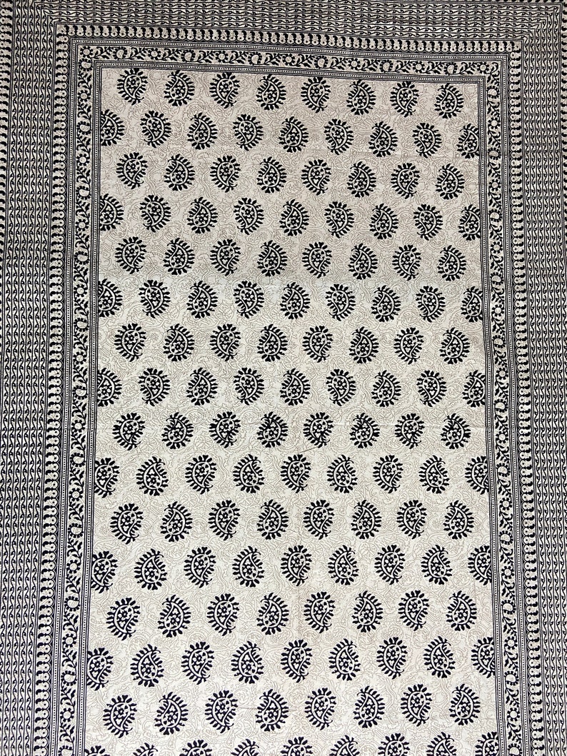 Peut inclure: Un tissu blanc avec un motif paisley noir. Le tissu a une bordure noire avec un motif r&eacute;p&eacute;titif.