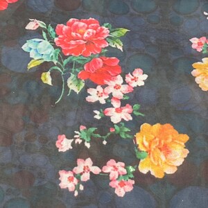 Puede incluir: Una tela azul oscuro con un estampado floral con flores rosas, rojas y amarillas. Las flores est&aacute;n dispuestas en un patr&oacute;n aleatorio y est&aacute;n rodeadas de hojas verdes.