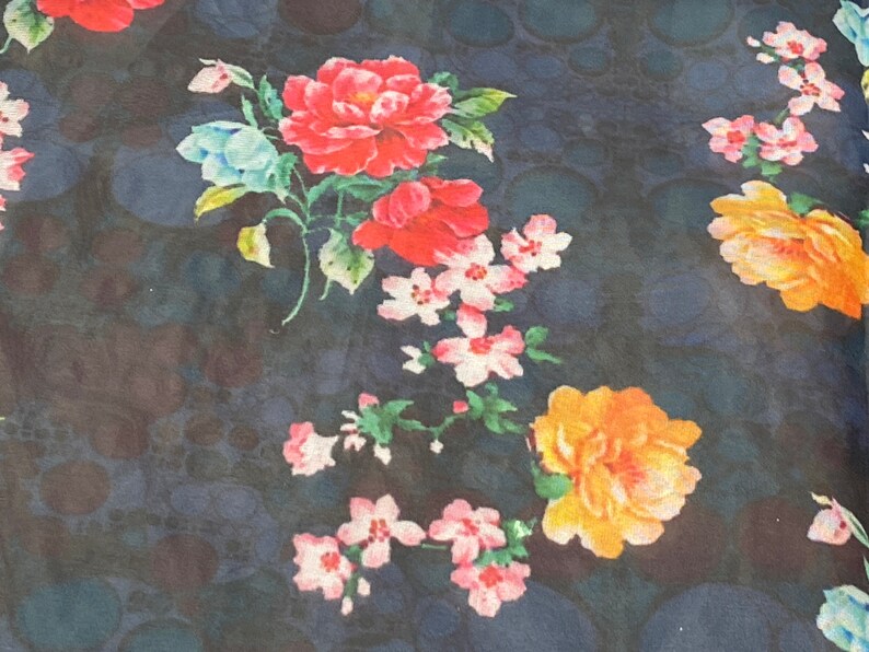 Puede incluir: Una tela azul oscuro con un estampado floral con flores rosas, rojas y amarillas. Las flores est&aacute;n dispuestas en un patr&oacute;n aleatorio y est&aacute;n rodeadas de hojas verdes.